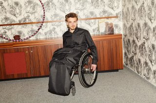 Model in einem dunklen Outfit in Rollstuhl