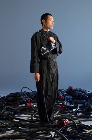 Model in einem schwarzen Outfit mit Handtasche