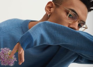 Model mit Brille in einem blauen Pullover