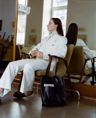 Model in einem weißem Outfit sitzend