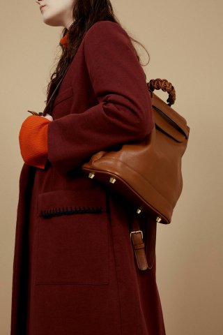 Model mit rotem Mantel und braunem Leder-Rucksack