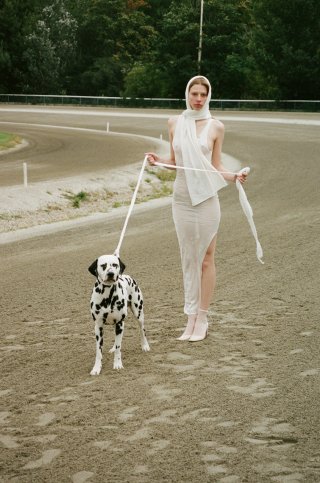 Model in weißem Outfit mit Dalmatiner Hund