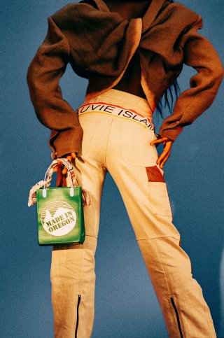Model in beiger Hose mit grüner Tasche