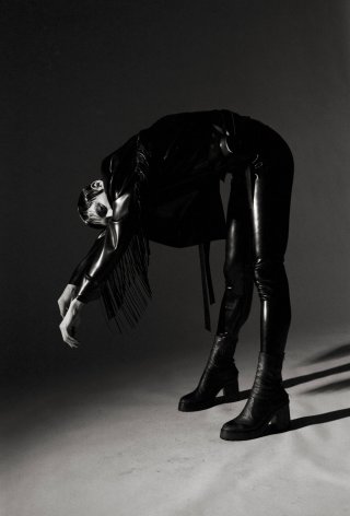 Model in schwarzem Outfit vor schwarzem Hintergrund