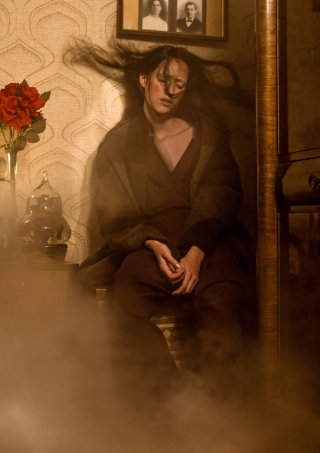 Model sitzt in einem dunklen Outfit