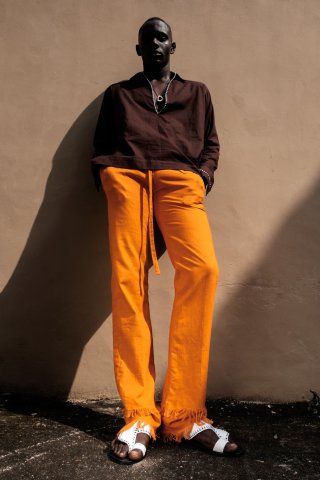 Model in oranger Hose und dunkelrotem Hemd