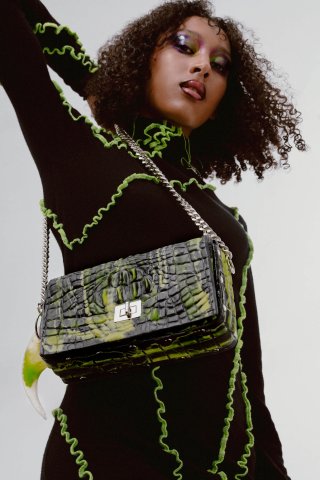 Foto von einem Model in einem schwarzen Oberteil mit grüner Naht. Model trägt eine schwarz-grüne Tasche von Ordained Hardware.