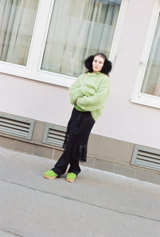 Model in schwarz-grünem Outfit mit Earmuffs