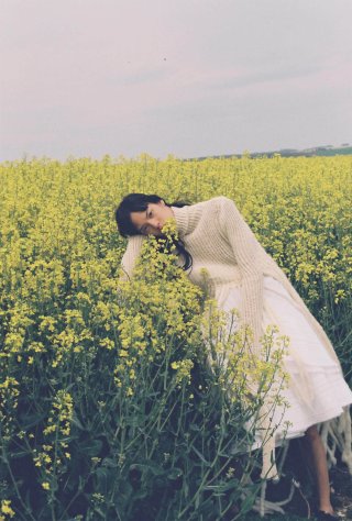 Model in einem Blumenfeld in einem weißen Kleid
