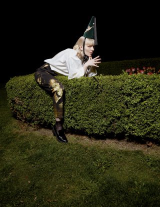 Blondes Model sitzt auf einem Busch