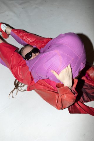 Model auf dem Boden in einem rot-pinken Outfit