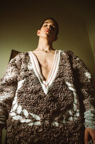 Model trägt einen braun-weiß gemusterten Pullover mit tiefem V-Ausschnitt.